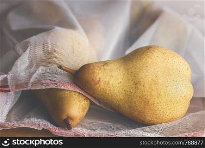 Groceries shopping in eco-friendly bags concept. Pears in a reusable mesh bag. Reduce plastic consumption. Plastic packaging problem control context.