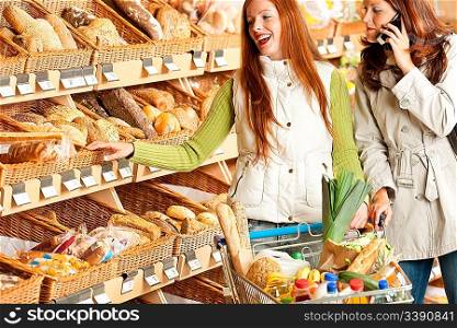 Grocery store: Red hair woman and brunette in winter outfit choosing bread