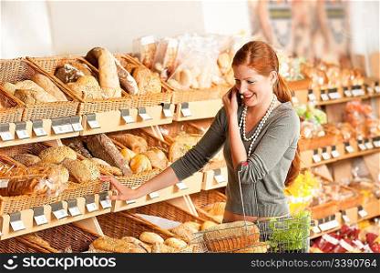 Grocery store: Red hair woman with mobile phone in a supermarket