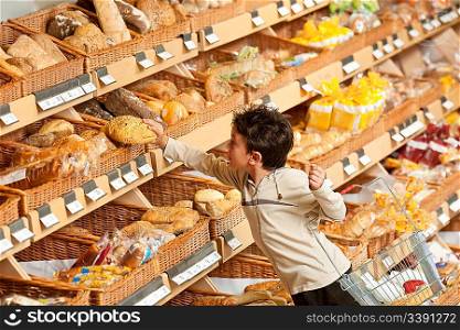 Grocery store shopping - Little boy buying bread in a supermarket