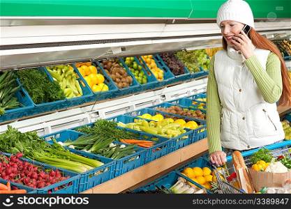 Grocery store shopping - Red hair woman with mobile phone in winter outfit