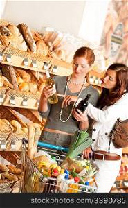 Grocery store: Two young women choosing wine in a supermarket