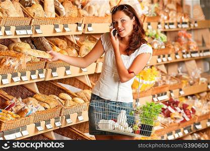 Grocery store: Young woman holding mobile phone and shopping basket