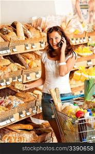 Grocery store: Young woman with mobile phone and shopping cart