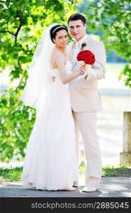 groom and bride in white dress on background of green trees