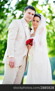 groom and bride in white dress on background of green trees