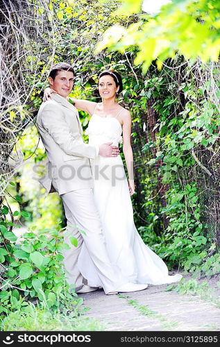 groom and bride in white dress on background of green trees