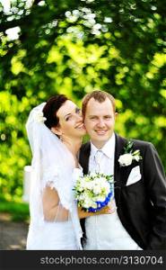 groom and bride in white dress on background of green trees