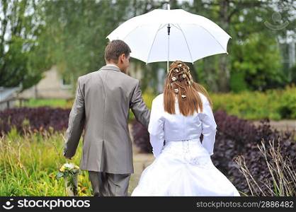 groom and bride walking in park