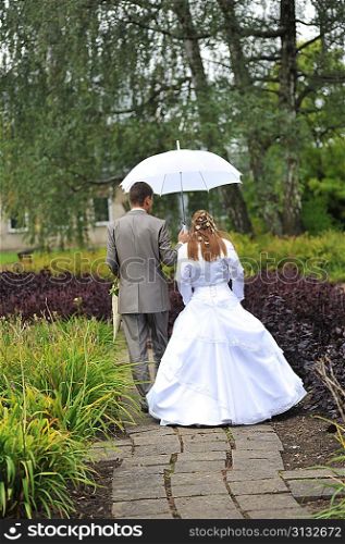 groom and bride walking in park