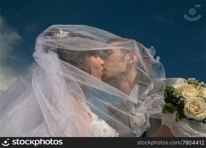 Groom and the bride embrace on a background of the dark blue sky.