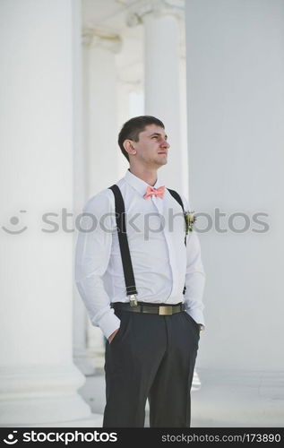 Groom at white columns.. Groom on the background of white columns 3923.