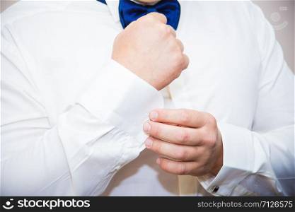 Groom buttons cuffs on his white shirt. Groom buttons cuffs on his shirt