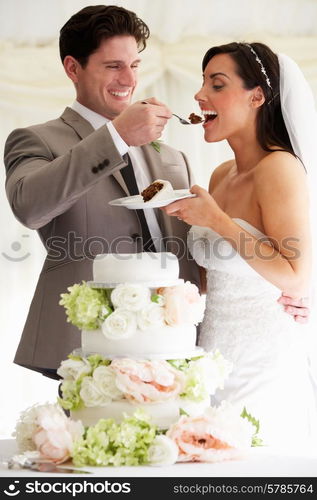 Groom Feeding Bride With Wedding Cake At Reception