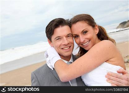 Groom holding bride in his arms at the beach