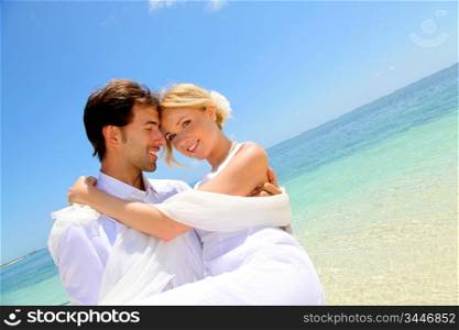 Groom holding bride in his arms by the sea