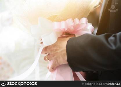 Groom holding rose flowers bouquet with sunlight in marriage. Valentine Day for love and celebration Concept.