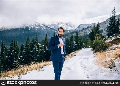 groom in a blue suit and bride in white, embroidered with blue pattern, dress on a background of green pine forests in the mountains of the Carpathians, smoking, cigar, smoke