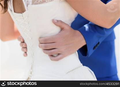 groom in a blue suit hugs the bride&rsquo;s waist