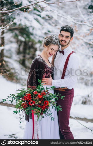 groom in a brown and bride in burgundy in the mountains Carpathians