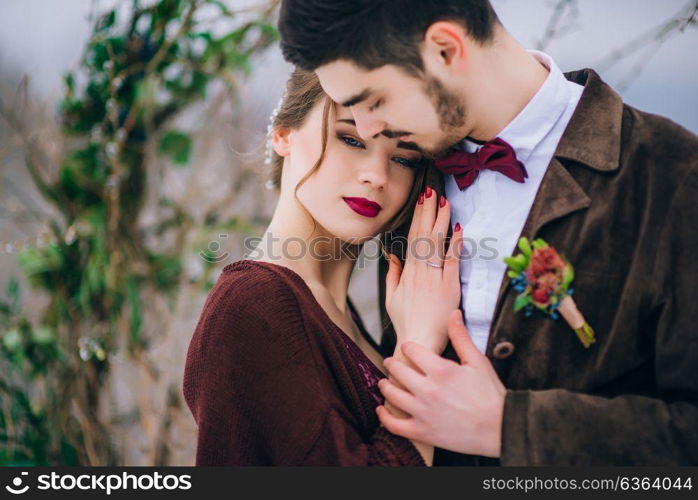 groom in a brown and bride in burgundy in the mountains Carpathians