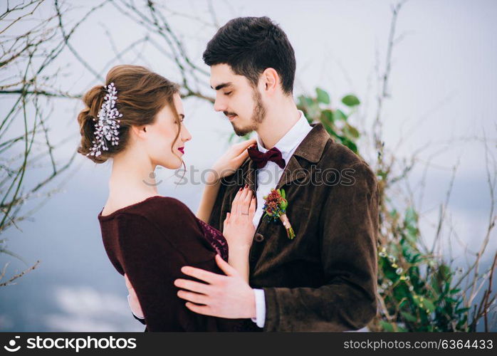 groom in a brown and bride in burgundy in the mountains Carpathians