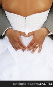 Groom making a heart sign while his arms are around his bride.