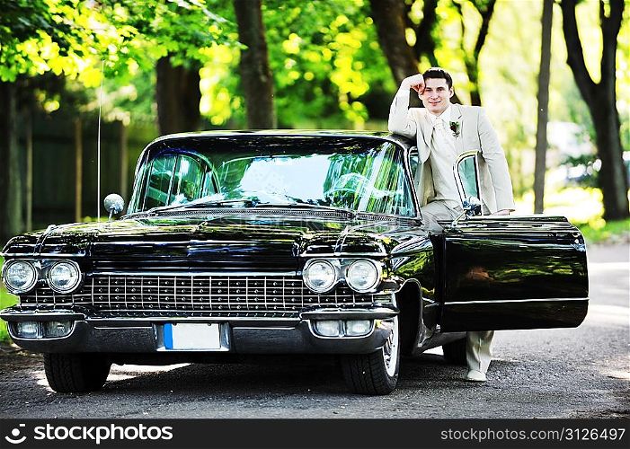 groom near car after their wedding ceremony