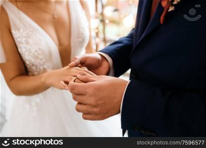 groom puts bride on wedding ring