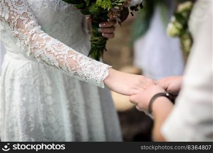 groom puts wedding ring on bride finger