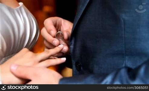 Groom putting a wedding ring on bride&acute;s finger