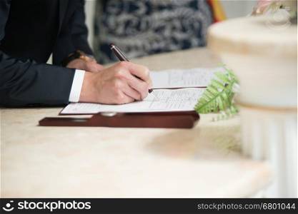 groom signs marriage certificate with a pen. wedding