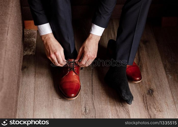 groom tied the laces on the shoes close up. business man is hanging shoes indoor in hotel room. mans hands and pair of leather men&rsquo;s shoes. meeting of the bridegroom. business man&rsquo;s morning. groom tied the laces on the shoes close up. business man is hanging shoes indoor in hotel room. mans hands and pair of leather men&rsquo;s shoes. meeting of the bridegroom. business man&rsquo;s morning.