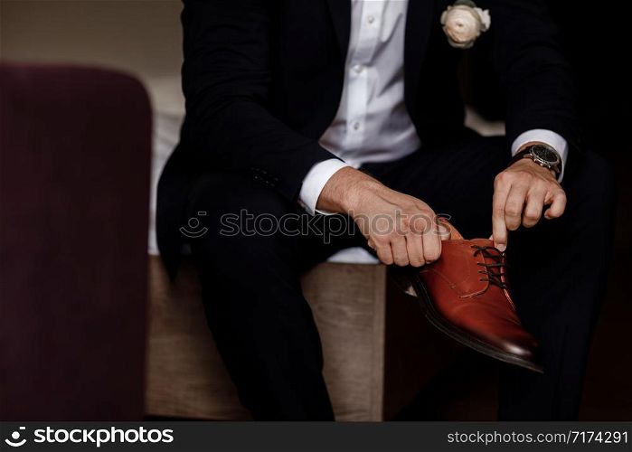 groom tied the laces on the shoes close up. business man is hanging shoes indoor in hotel room. mans hands and pair of leather men&rsquo;s shoes. meeting of the bridegroom. business man&rsquo;s morning. groom tied the laces on the shoes close up. business man is hanging shoes indoor in hotel room. mans hands and pair of leather men&rsquo;s shoes. meeting of the bridegroom. business man&rsquo;s morning.