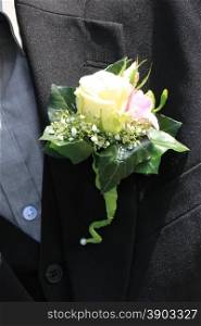 Groom wearing boutonniere: ivory rose and pink freesia