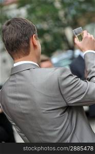 groom with gray jacket salutes with champagne