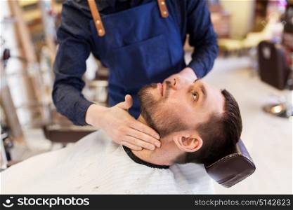 grooming and people concept - barber applying aftershave lotion to male neck at barbershop. barber applying aftershave lotion to male neck