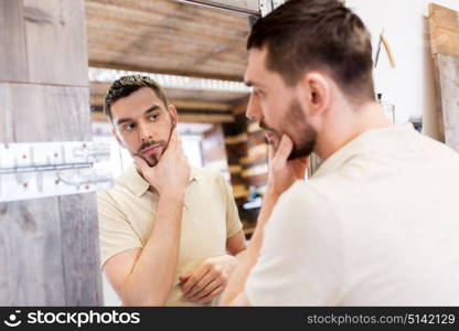 grooming and people concept - man looking at himself at barbershop mirror. man looking at himself at barbershop mirror