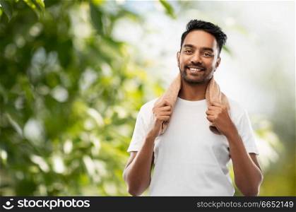 grooming and people concept - smiling indian man with bath towel over green natural background. smiling indian man with towel