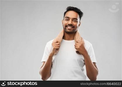 grooming and people concept - smiling indian man with bath towel over grey background. smiling indian man with towel over grey background