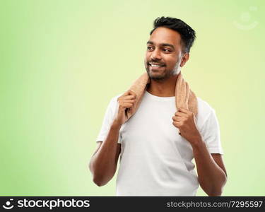 grooming and people concept - smiling indian man with bath towel over lime green natural background. smiling indian man with towel over green 