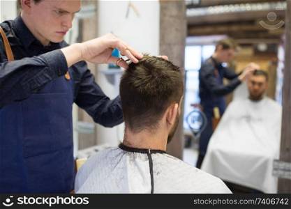 grooming, hairdressing and people concept - male client and hairdresser with scissors cutting hair at barbershop. male hairdresser cutting hair at barbershop
