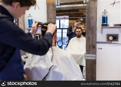 grooming, hairdressing and people concept - man and barber cutting hair at barbershop. man and barber cutting hair at barbershop