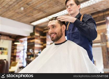 grooming, hairdressing and people concept - man and barber styling hair at barbershop. man and barber styling hair at barbershop