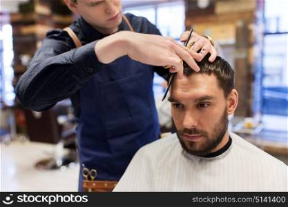 grooming, hairdressing and people concept - man and barber with comb and scissors cutting hair at barbershop. man and barber cutting hair at barbershop