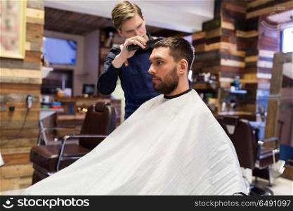 grooming, hairdressing and people concept - man and barber with comb and scissors cutting hair at barbershop. man and barber cutting hair at barbershop. man and barber cutting hair at barbershop