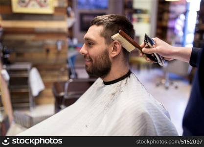 grooming, hairdressing and people concept - man and barber with trimmer and brush cleaning hair at barbershop. man and barber with brush cleaning hair at salon