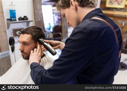 grooming, hairstyle and people concept - man and barber or hairdresser with trimmer cutting hair at barbershop. man and barber with trimmer cutting hair at salon