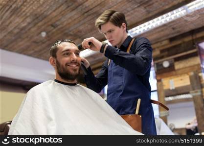 grooming, hairstyle and people concept - man and barber or hairdresser with trimmer cutting hair at barbershop. man and barber with trimmer cutting hair at salon