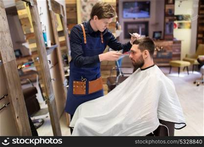 grooming, hairstyle and people concept - man and barber or hairdresser with trimmer and comb cutting hair at barbershop. man and barber with trimmer cutting hair at salon